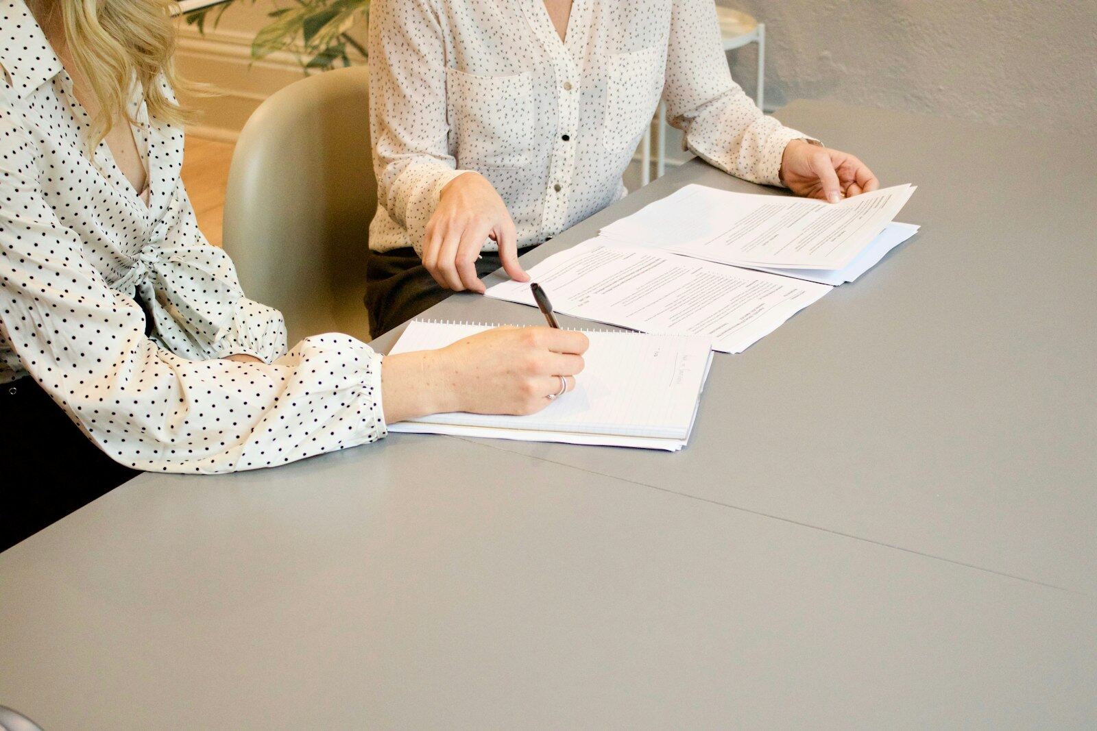 Two consultants reviewing and signing documents at a desk
